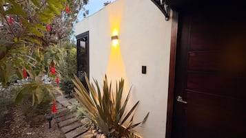 Fachada de una casa con un accesorio de luz, una puerta de madera y un camino de piedra.