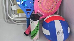 A rack with sports equipment including a blue and pink paddle, a can of tennis balls, and a volleyball. - Cozy apartment with sea view Posto 2 Copacabana (Copacabana Rio de Janeiro)
