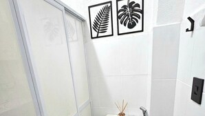 A bathroom with a toilet, bidet, and shower. There are two framed wall art pieces above the toilet. - Cozy apartment with sea view Posto 2 Copacabana (Copacabana Rio de Janeiro)