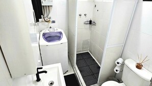 A compact bathroom with a white sink, a toilet, and a shower enclosure. - Cozy apartment with sea view Posto 2 Copacabana (Copacabana Rio de Janeiro)