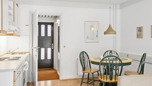 A compact kitchen with a stove, sink, and a door leading to a hallway.