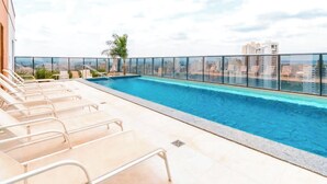 A rooftop pool with clear blue water, surrounded by a glass railing, and overlooking a cityscape. - STAY Metropolitan Barcelona  (Goiania)