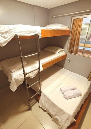 Ein Schlafzimmer mit Etagenbetten, einer Leiter, einem Fenster mit Vorhängen und einem Nachttisch.