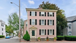 A pink two-story building with a green door and multiple windows.