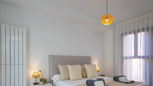 A modern bedroom with a bed, bedside tables, and a hanging light fixture.