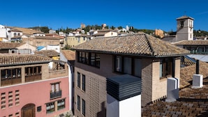 Un bâtiment traditionnel avec un toit en tuiles, un balcon bien visible et un clocher en arrière-plan.