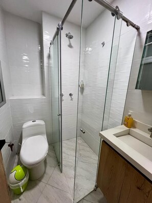 A modern bathroom with a glass-enclosed shower, a toilet, and a sink with a mirror above it. - Guayacan (Guatapé)