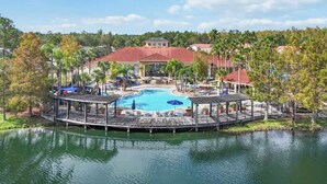 A resort with a central swimming pool, a covered deck area, and a view of the surrounding landscape.