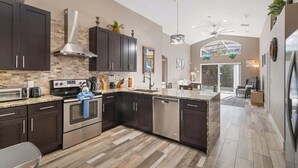 A modern kitchen with dark cabinetry, stainless steel appliances, and a large island.