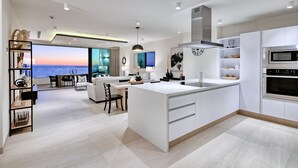 Una cocina moderna con una isla grande, electrodomésticos integrados y vista al océano.