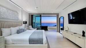 Un dormitorio moderno con una cama grande, un televisor y vistas al océano.