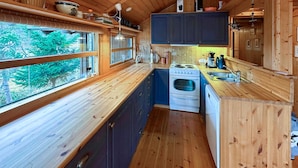 A compact kitchen with wooden cabinets, a stove, and a sink. - 3 bedroom cozy home in Tjørhom (Tjørhom)