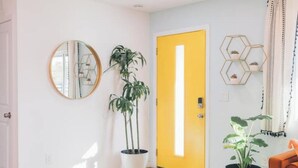 A bright hallway with a yellow door, a round mirror, and potted plants. - Casa De Colores w/ Arcade, hot tub + more - J Tree

 (Joshua Tree)