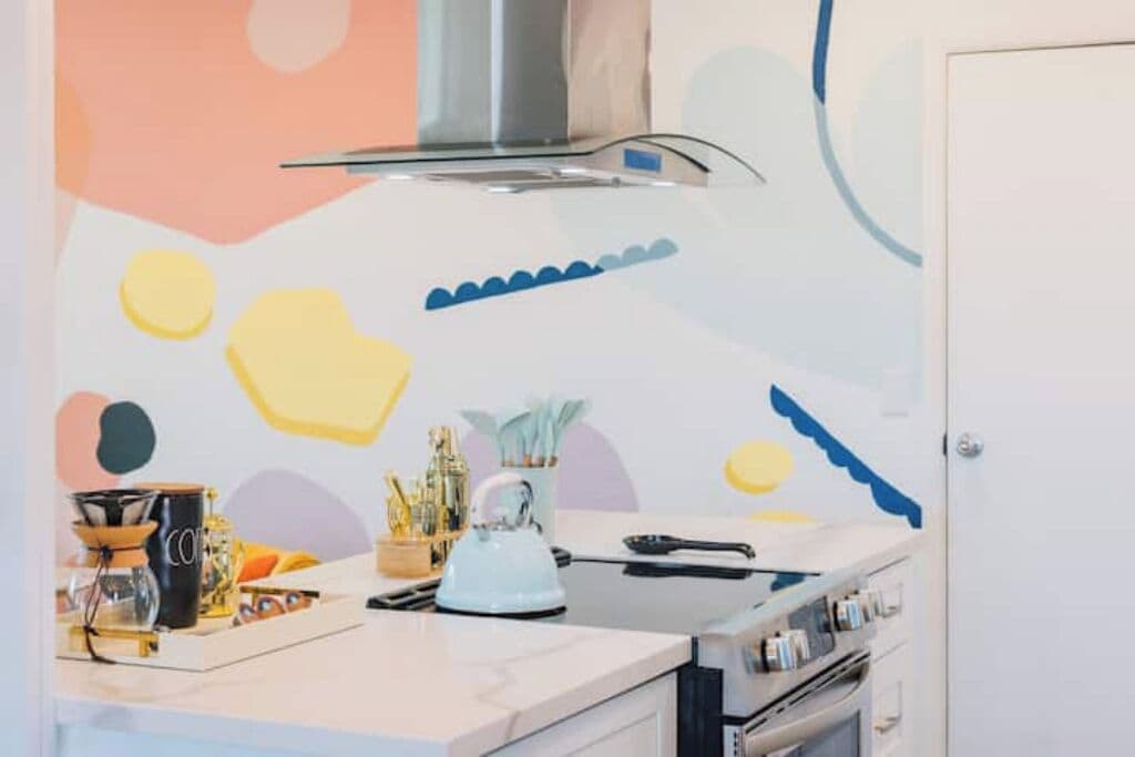 Een keuken met een modern design, met een wit aanrecht, een waterkoker en diverse keukengerei.
