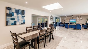 A modern dining area with a marble floor, a large abstract painting, and a dining table with chairs. - Family Escape w/ 5 bedrooms, pool, hot tub & canal (Cape Coral)