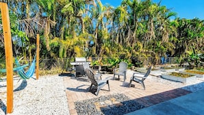 A patio area with outdoor seating, a grill, and lush tropical vegetation. - Family Escape w/ 5 bedrooms, pool, hot tub & canal (Cape Coral)