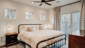 A bedroom with a bed, bedside tables, a ceiling fan, and windows.
