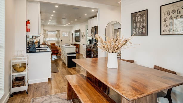 A modern kitchen with wooden countertops, a central island, and a dining area with a wooden table and benches.