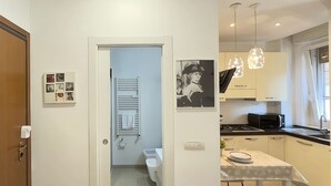 Een moderne keuken met een eethoek, een witte radiator en een aan de muur hangend schilderij.