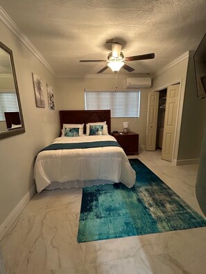 Relax in this serene bedroom with a large bed, nightstands, and a ceiling fan above.
