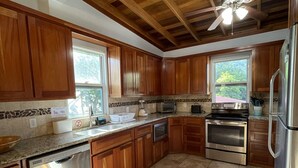 Una cocina con armarios de madera, lavavajillas, estufa y refrigerador.