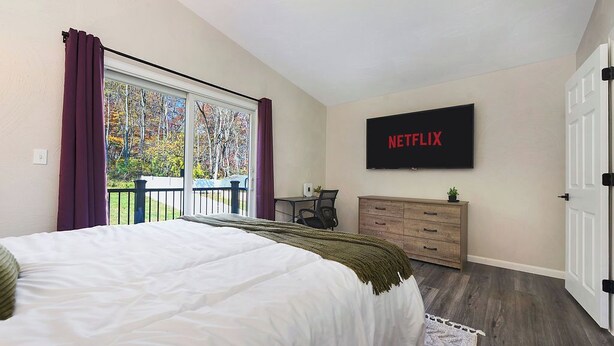 Un dormitorio con una cama grande, un televisor montado en la pared, un escritorio y un aparador.