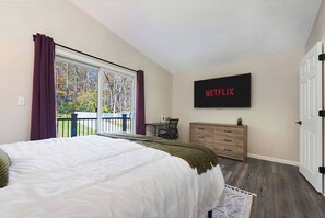 Ein Schlafzimmer mit einem großen Bett, einem an der Wand montierten Fernseher, einem Schreibtisch und einer Kommode.