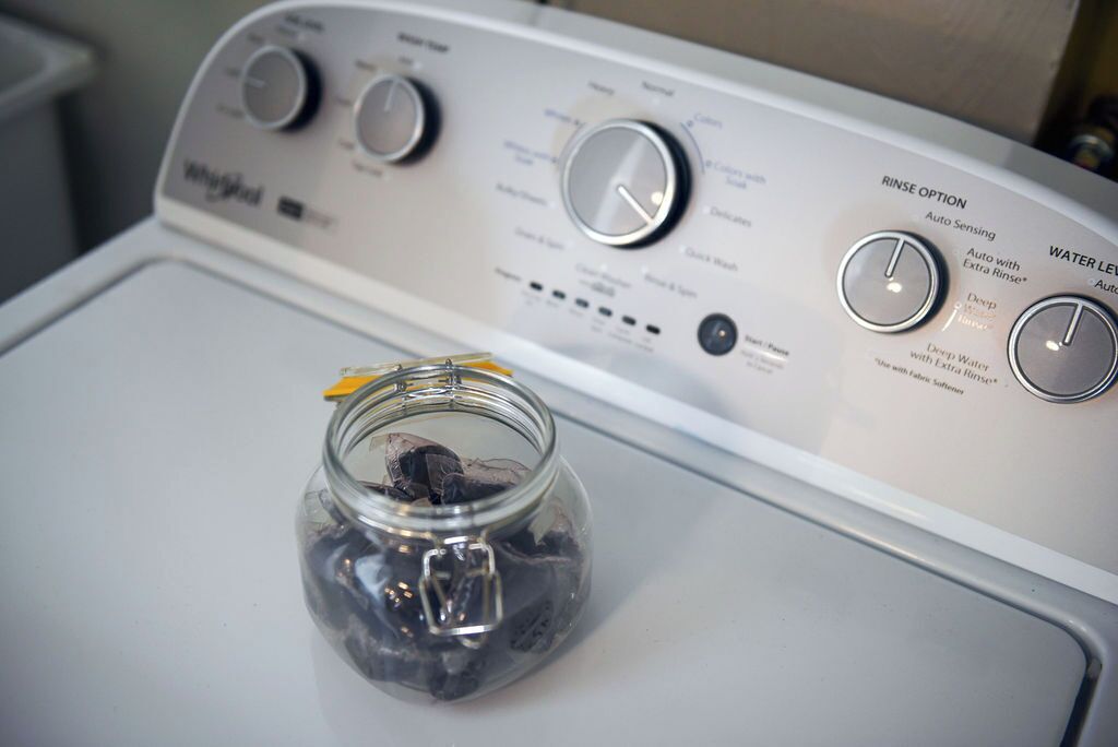 Una lavadora Whirlpool de carga frontal con perillas de control y un manual.