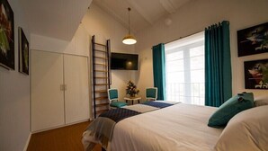 Een slaapkamer met een bed, twee stoelen, een tafeltje, een televisie en een kledingkast.