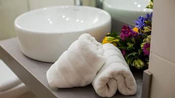 A bathroom with a white sink, a towel, and a bouquet of flowers.