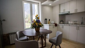 Een moderne keuken met witte kasten, een eettafel met stoelen en een raam met bloemenarrangement.