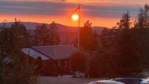 A sunset with a flag on a flagpole, surrounded by trees and a building.