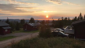 A rural setting with a dirt road, a red barn, and a row of parked cars. - 4 Star Holiday Home in Syssleback (Sysslebäck)
