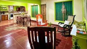 A spacious living area with a dining table, chairs, and a kitchen in the background. - Green Hostel (Moyagalpa)