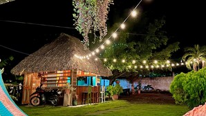A thatched-roof hut with a motorcycle parked in front, surrounded by greenery and string lights. - Green Hostel (Moyagalpa)
