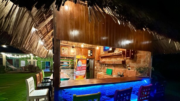 An outdoor bar area with wooden furniture, a counter, and a thatched roof. - Green Hostel (Moyagalpa)
