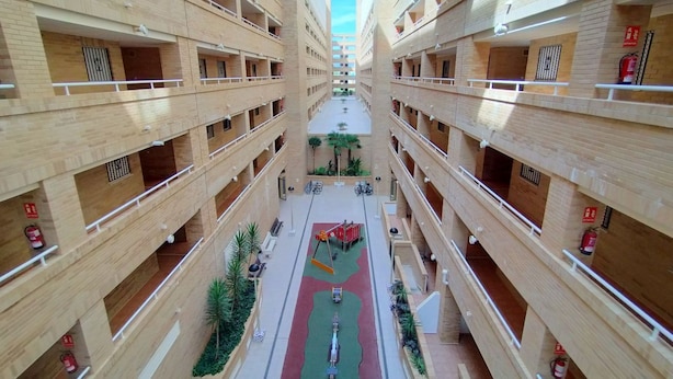 Un edificio de varios pisos con un patio central, balcones en cada nivel y equipo de seguridad contra incendios.