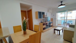 Una sala de estar moderna con comedor, un sofá, una televisión y un balcón con vistas.