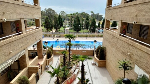 Un área de piscina de varios niveles con una piscina central, rodeada de muros de ladrillo y plantas en macetas.