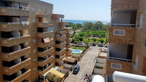 Un edificio residencial de varios pisos con balcones, piscina y vista al mar.