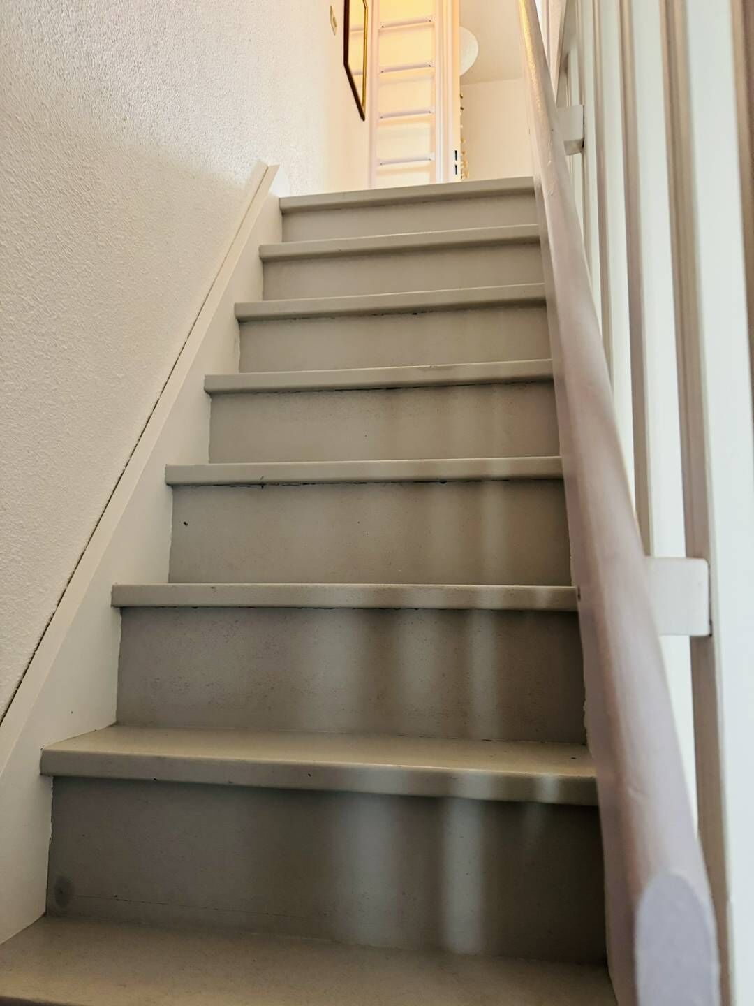 Een trap met een leuning en een lamp bovenin.