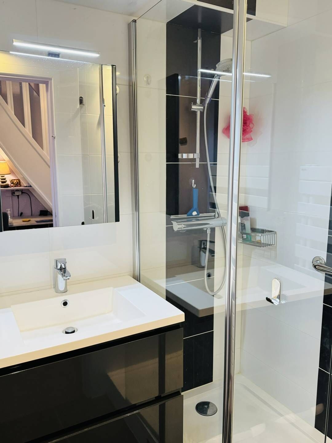A modern bathroom with a glass-enclosed shower, a white sink, and a mirror.