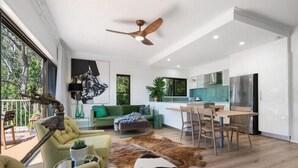 A modern living space with a dining area, kitchen, and a large window overlooking greenery. - Currumbin Escape 2 BDR Water Views (Currumbin)