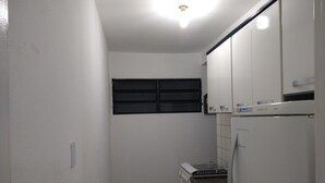 A compact kitchen with white cabinets, a built-in oven, a microwave, and a refrigerator. - Round trip - LA07-Bertioga, SESC, Riviera, Vista Linda, Indaiá (Jardim Rafael Bertioga)