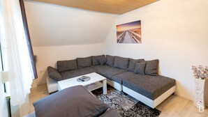 Een moderne woonkamer met een modulaire bank, een klein wit tafeltje en een decoratief wandkunstwerk.