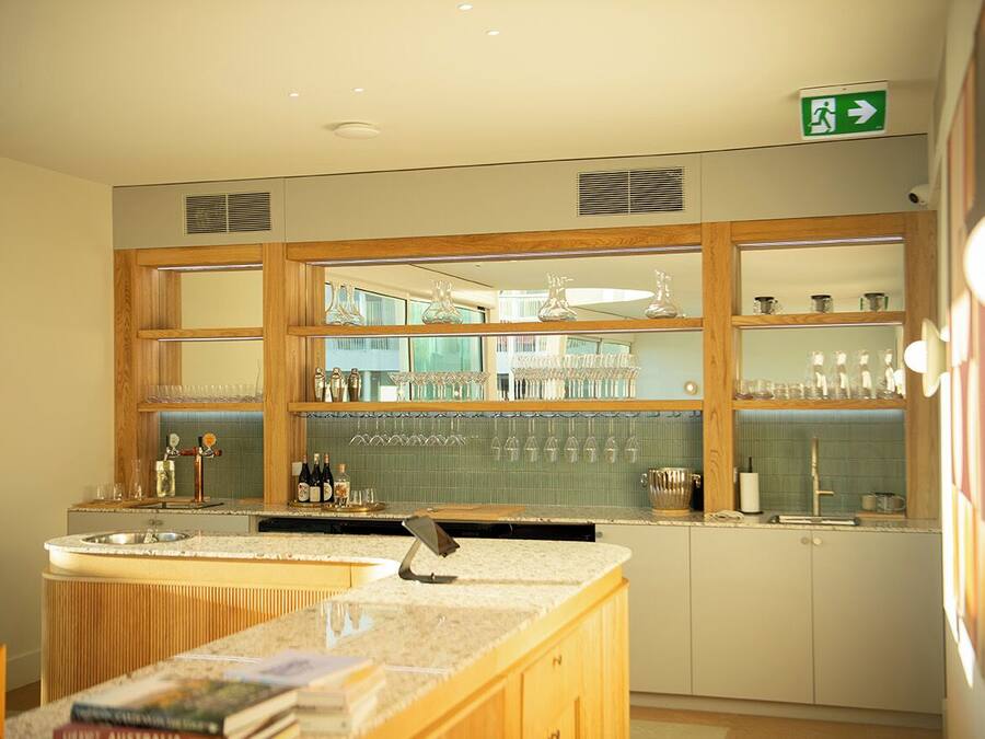 A kitchen with a bar area, wooden cabinets, and a countertop with a sink.