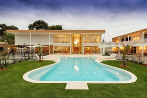 Una casa moderna con piscina, ventanas amplias y un césped cuidado.
