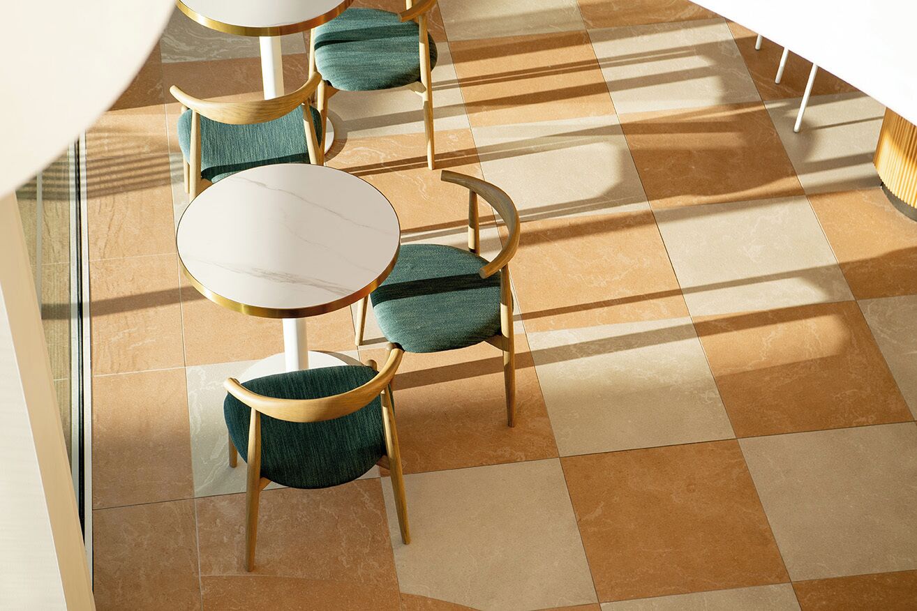 A modern interior with checkered flooring, round tables, and wooden chairs with teal cushions.