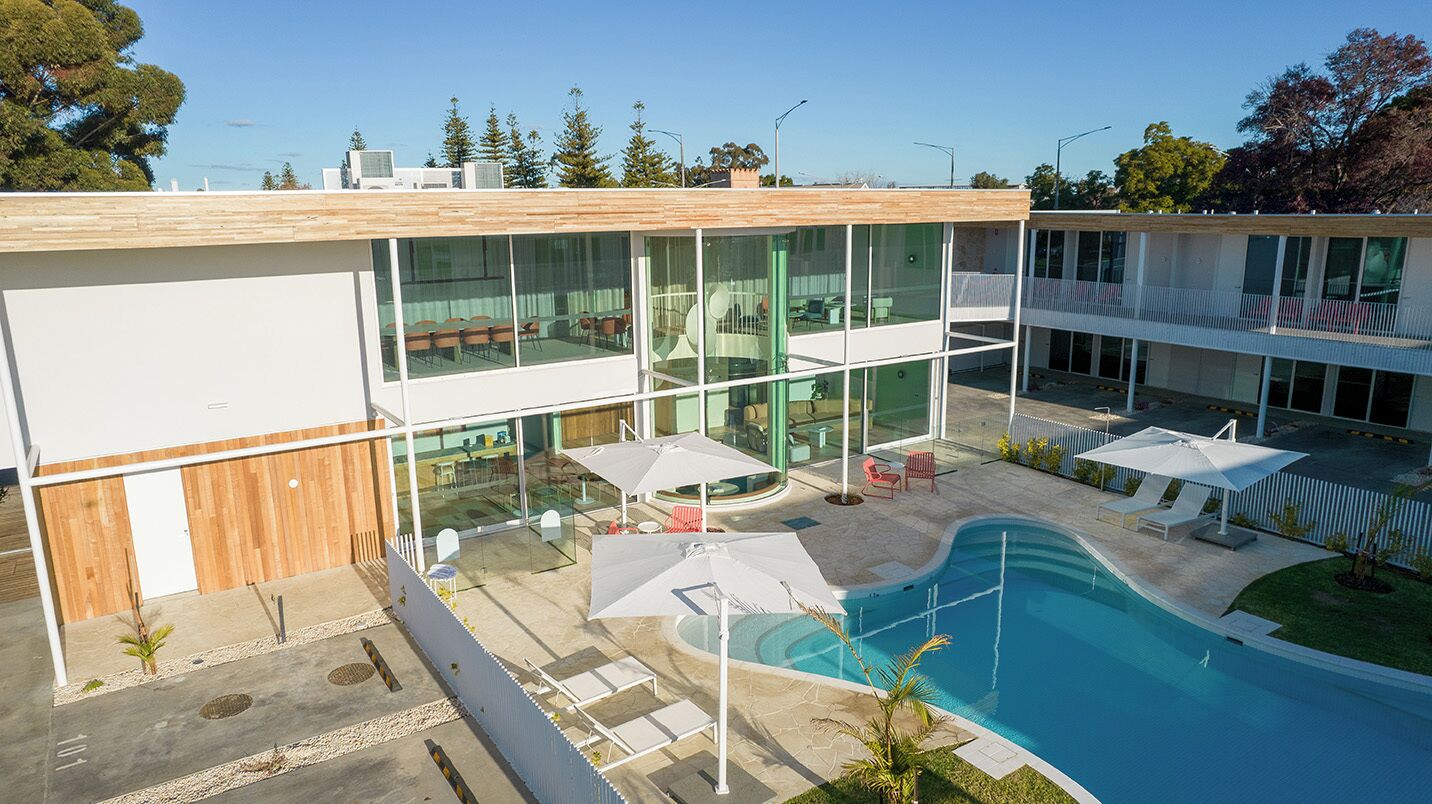Um edifício moderno com piscina, área de estar externa e paredes de vidro.