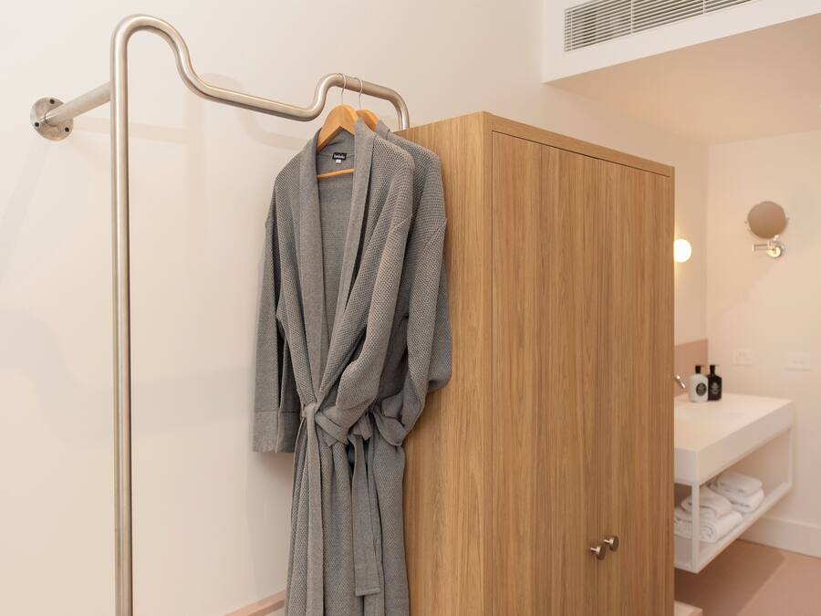 A bathroom with a wooden wardrobe, a towel rack, and a sink with toiletries.
